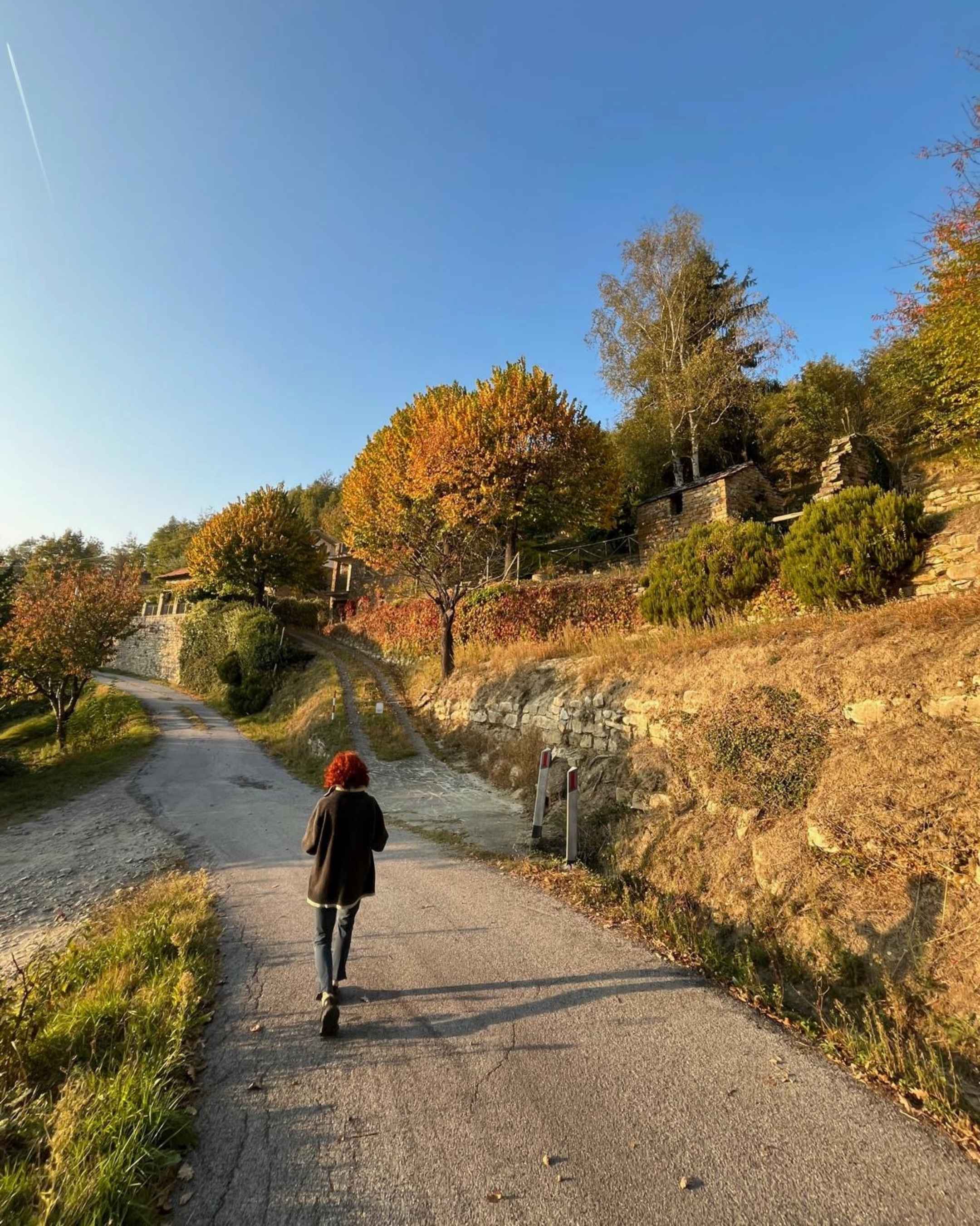A woman walks in Alta Langa at golden hour in October.