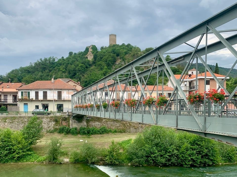 A bridge over the Bormida river with Cortemilia's houses and tower on the other side.