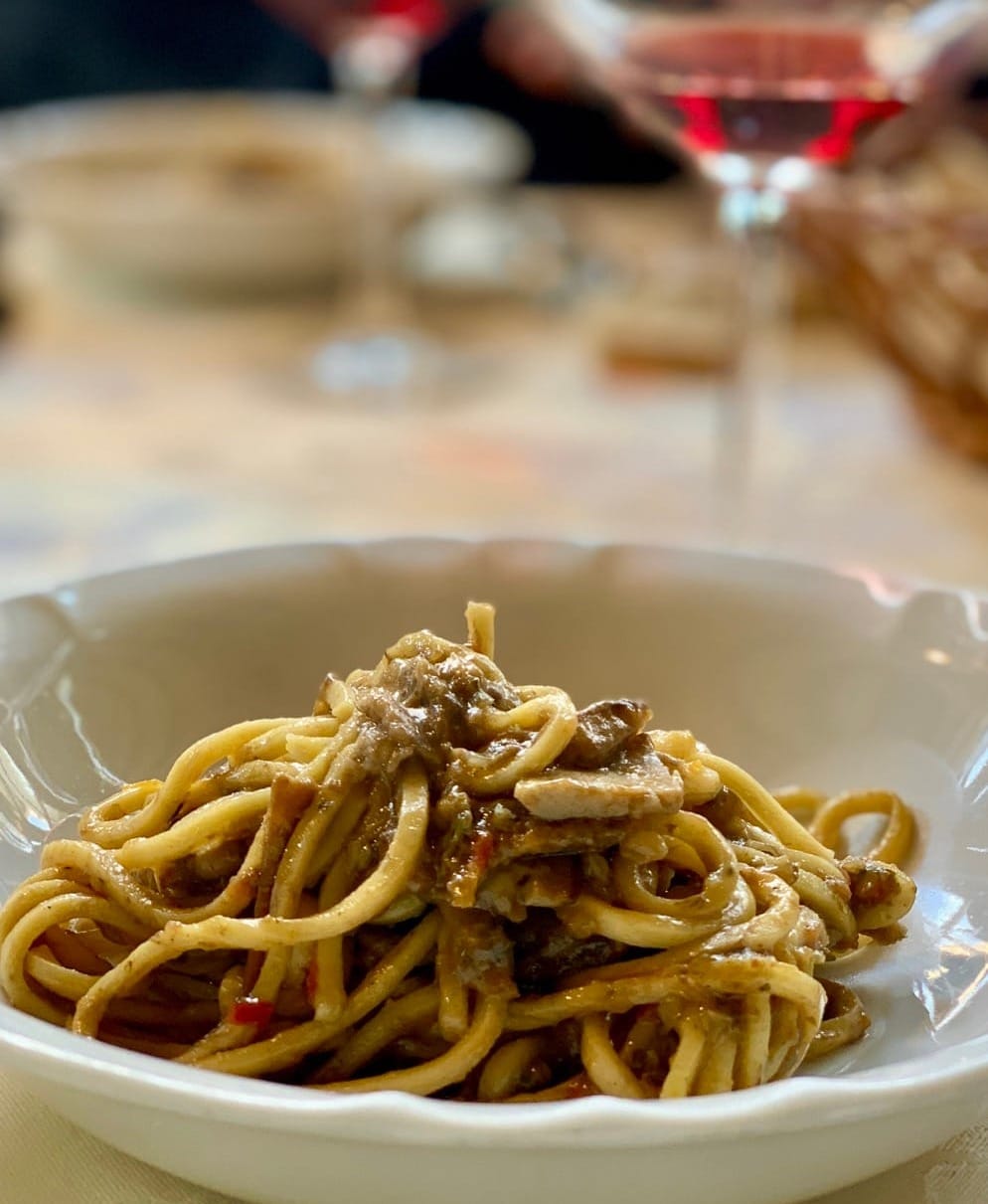 Tajarin with funghi (mushrooms) and a glass of wine in the background. 